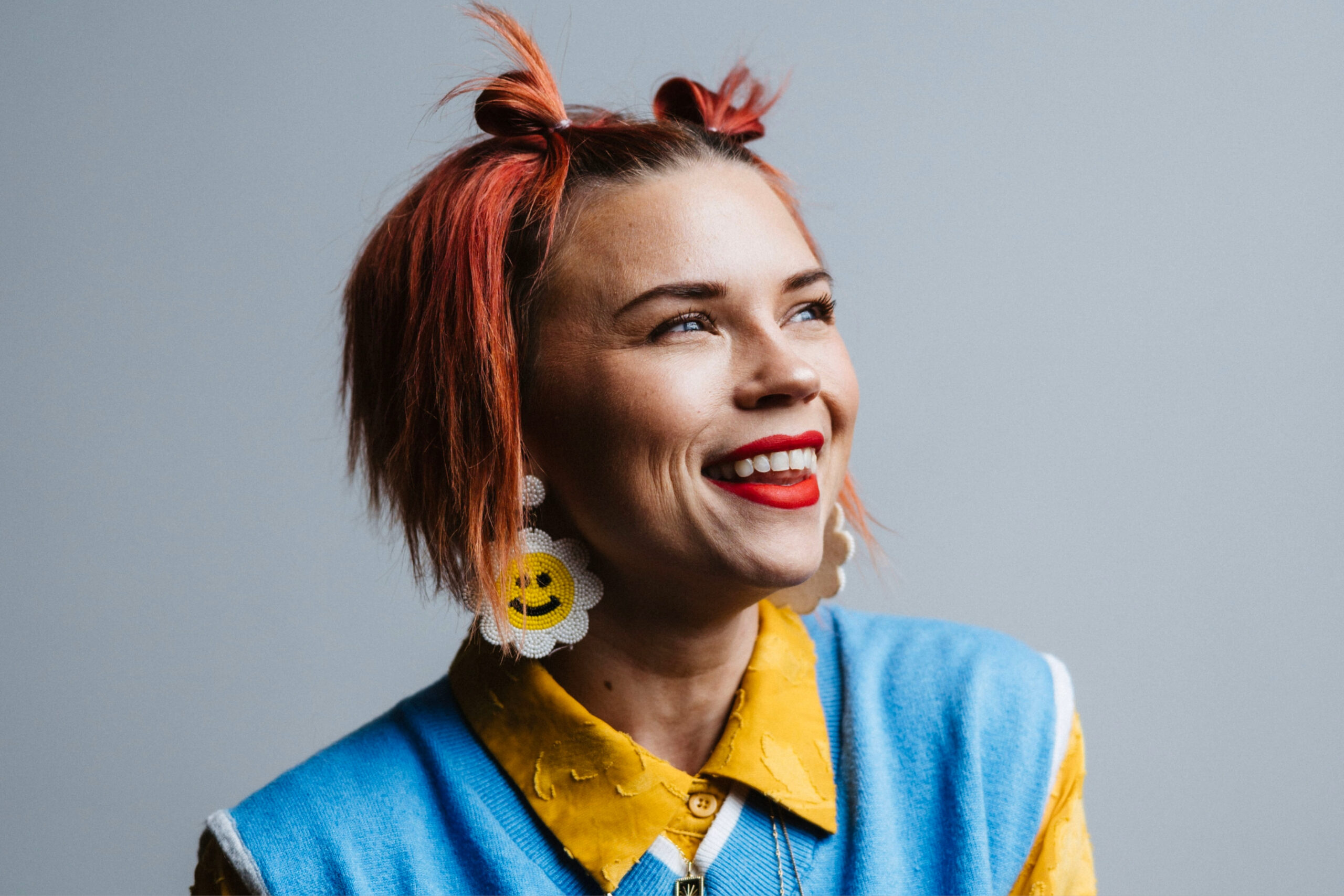 Franklin, Tennessee resident and child advocate, Anna Skates smiles wearing smiley, flower earrings and vibrant, yellow and blue, clothing.